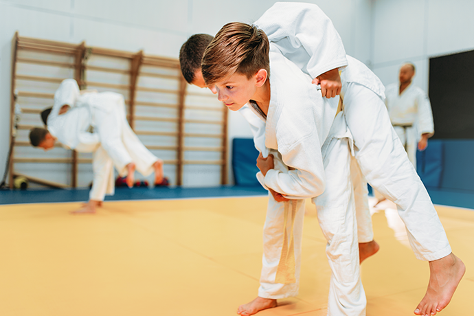 Kuva lapsista judosalissa. kuvassa toinen lapsi on tekemässä judoheittoa